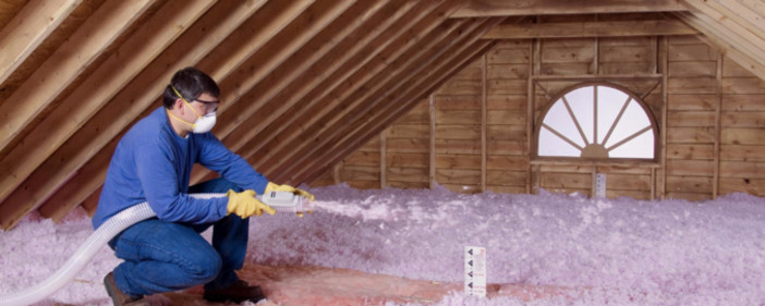 Installer blowing insulation in an attic